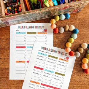 May include: Two printable weekly cleaning checklists with colorful headings and checkboxes. The checklists are titled "Weekly Cleaning Checklist" and "Weekly Cleaning Checklist: Kitchen/Laundry Room".