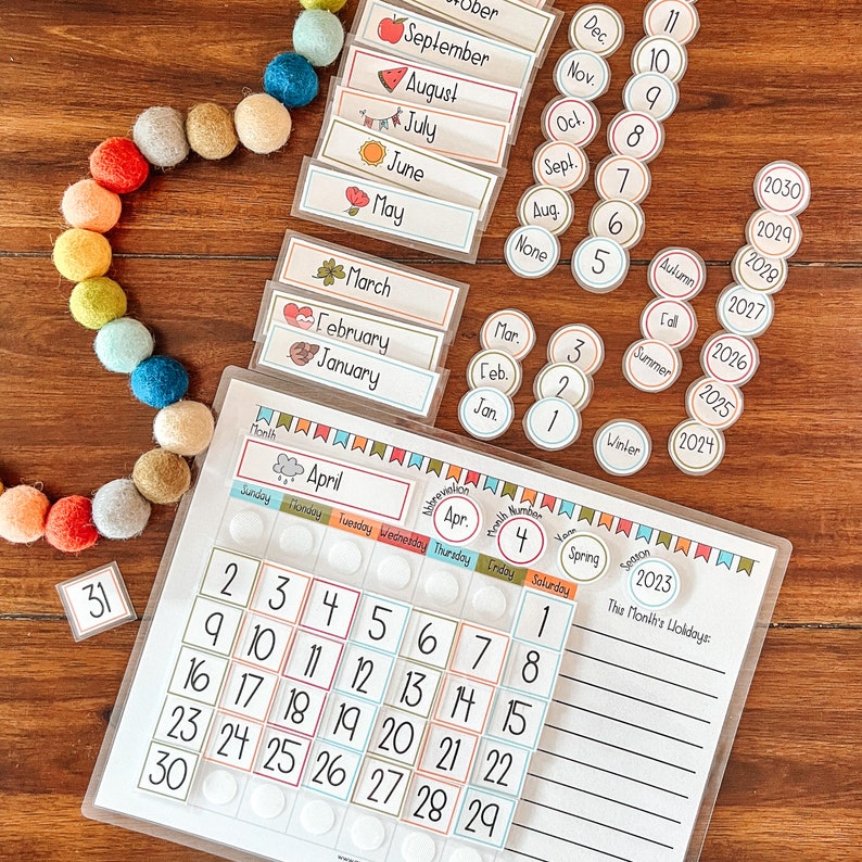 Puede incluir: Un calendario colorido con una cubierta de pl&aacute;stico transparente. El calendario presenta una cuadr&iacute;cula con los n&uacute;meros del 1 al 30, y el mes de abril est&aacute; resaltado. Tambi&eacute;n hay peque&ntilde;os c&iacute;rculos con los n&uacute;meros del 1 al 11, y las palabras "Primavera", "Verano", "Oto&ntilde;o" e "Invierno" son visibles. El calendario est&aacute; sobre una superficie de madera.