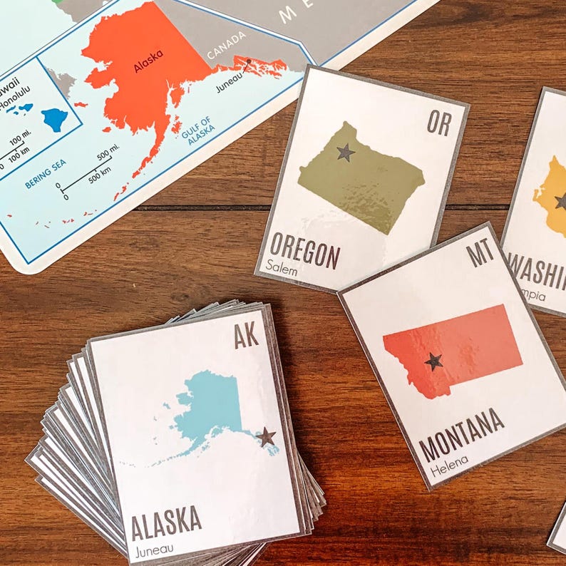 Pu&ograve; includere: Un mucchio di carte bianche con i contorni e i nomi degli stati, tra cui Alaska, Oregon e Montana. Ogni carta mostra la forma di uno stato in un colore solido, con una stella che indica la capitale. Sullo sfondo &egrave; visibile una mappa dell'Alaska e del Canada.