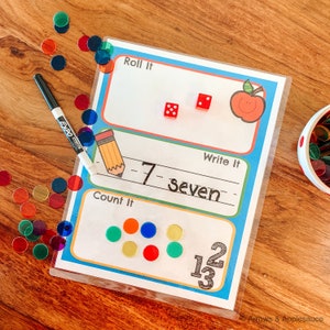 K&ouml;nnte beinhalten: Ein farbenfrohes Lernspiel f&uuml;r Kinder mit einem roten Apfel, W&uuml;rfeln und Z&auml;hlern. Das Spiel enth&auml;lt die W&ouml;rter "Roll It", "Write It" und "Count It".