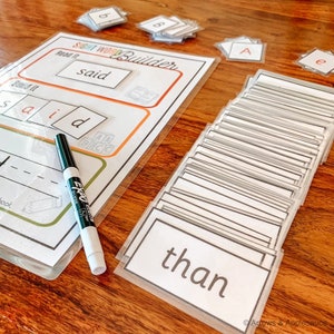 May include: A worksheet with the words "Sight Word Builder", "Read it", "said", and "Build it" printed on it. There are blank spaces for students to write the word "said" and a dry erase marker is on the table. There are also several cards with sight words on them, including the word "than".