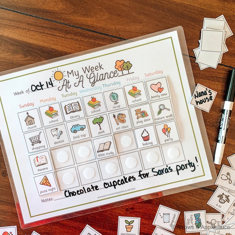 K&ouml;nnte beinhalten: Ein transparenter Wochenplaner aus Plastik mit gr&uuml;nem Rand und dem aufgedruckten Text "My Week At A Glance". Der Planer ist in Wochentage unterteilt, wobei jeder Tag ein Raster aus Feldern f&uuml;r Aktivit&auml;ten hat. Die Felder sind mit kleinen Bildern gef&uuml;llt, die verschiedene Aktivit&auml;ten darstellen, wie z. B. Kirche, Schule, Bibliothek, Park, Kunstunterricht, Verabredung, Spaziergang in der Natur, Backen und Party. Der Planer enth&auml;lt auch einen Notizbereich am unteren Rand.