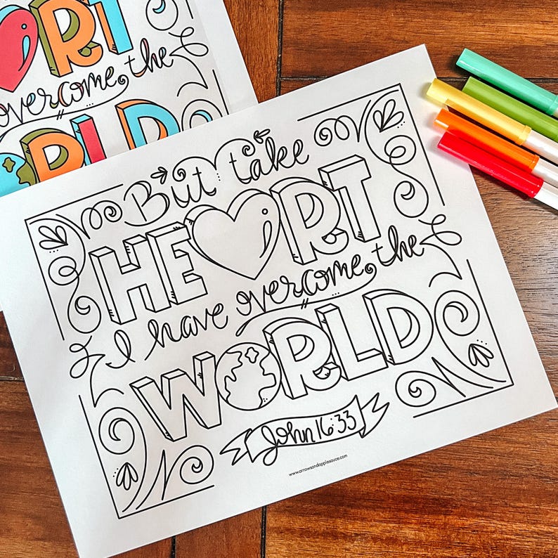 May include: Two white coloring pages with the words "But take heart, I have overcome the world" and "John 16:33" in black, outlined letters. The word "HEART" is in large, 3D letters. Colored markers in red, orange, yellow, green, and blue are visible.