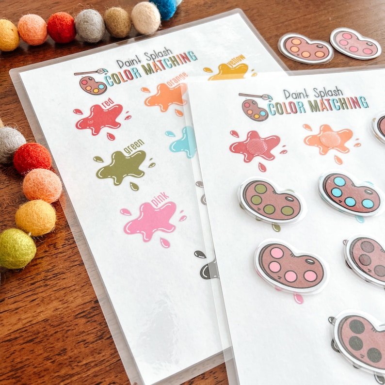 Puede incluir: Dos hojas de trabajo imprimibles para un juego de coincidencia de colores de salpicaduras de pintura. Las hojas de trabajo presentan salpicaduras de pintura de diferentes colores, con las palabras "rojo", "naranja", "amarillo", "verde", "azul" y "rosa" impresas junto a cada salpicadura. Las hojas de trabajo tambi&eacute;n incluyen una paleta de pintura con pozos de pintura de diferentes colores.