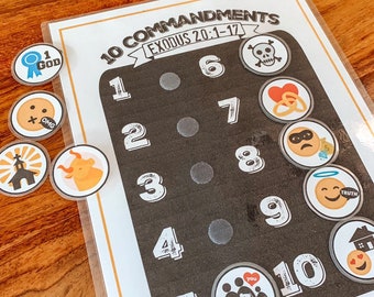 May include: A black chalkboard with white numbers 1 through 10. The numbers are in a circle with a white dot in the center. There are 10 colorful stickers with different images on them. The stickers are placed on the chalkboard next to the numbers. The text on the chalkboard reads "10 Commandments Exodus 20:1-17".