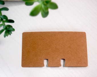 May include: A brown cardboard card with three cut-out slots at the bottom.