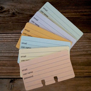 May include: A stack of six colorful index cards with lines for writing down email addresses, user names, and passwords. The cards are arranged in a fan shape with the top card being light blue and the bottom card being peach.