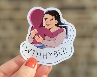 Op de afbeelding: Een sticker met een cartoonillustratie van twee mensen die elkaar omhelzen. De persoon vooraan draagt een roze hoodie en de persoon achteraan draagt een lichtroze shirt. De tekst "WTHHYBL?!" staat in een witte spraakballon.