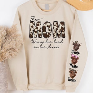 a sweater with the word mom written on it next to a vase with dried flowers