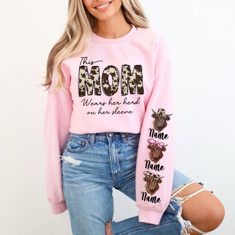 a woman wearing a pink mom sweatshirt and jeans