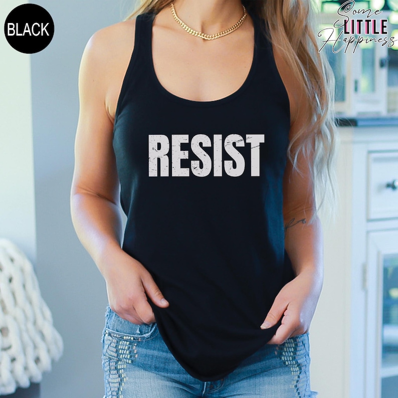 May include: A black tank top with the word "RESIST" printed in white on the front. The tank top is being worn by a person.