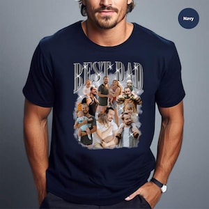 May include: A navy blue t-shirt with the text "BEST DAD" in silver glitter letters. The shirt features a collage of photos of a man with children.