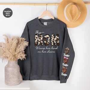 a sweater with the word mom on it next to a plant