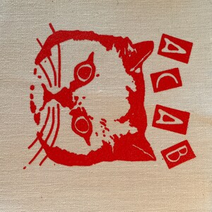 K&ouml;nnte beinhalten: Roter gestickter Aufn&auml;her mit einem Katzenkopf und den Buchstaben "ACAB" dar&uuml;ber.