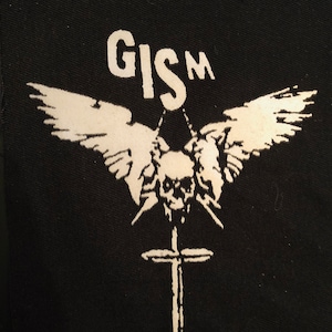以下が含まれることがあります： 白黒のパッチで、ドクロと交差した骨のデザイン。ドクロは2つの翼で囲まれており、その上に「GISM」という文字が書かれている。