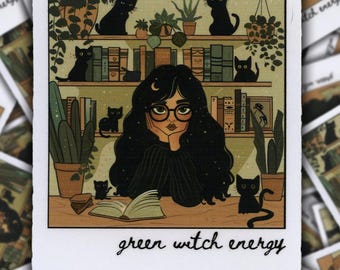 May include: A digital illustration of a woman with long black hair and glasses sitting at a table with a book open in front of her. She is surrounded by plants, books, and black cats. The text "green witch energy" is written below the image.