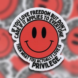 May include: A white sticker with a red smiley face and black text that reads: "If you love freedom but don't care if it applies to everyone then what you actually love is privilege."