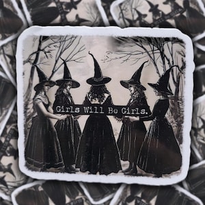 May include: A sticker with a vintage illustration of five women in witch hats and long dresses. The text "Girls Will Be Girls" is displayed across the center. The background includes bare trees, creating a spooky, gothic aesthetic.