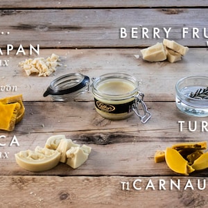 May include: A variety of natural waxes, including beeswax, carnauba wax, myrica berry wax, and Japan wax, are displayed on a wooden surface.  The waxes are in various forms, including chunks, flakes, and a jar of beeswax.