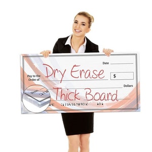 May include: A large dry erase board with the words "Dry Erase Thick Board" in red script. The board has a check design with lines for "Date" and "Dollars". A woman in a black suit holds the board.