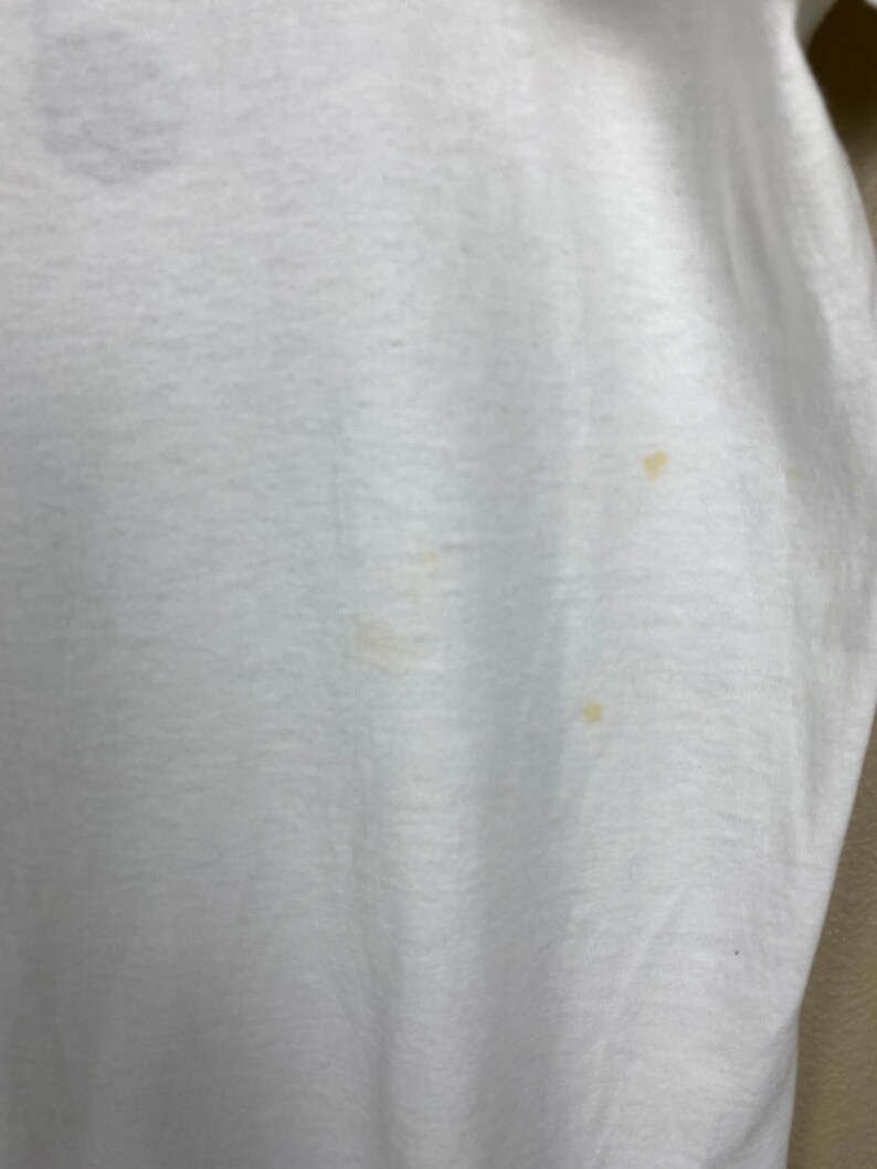 May include: White t-shirt with a few small yellow stains.