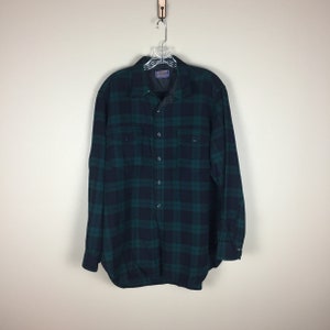Può includere: Una camicia di flanella a quadri verde e nero con bottoni e maniche lunghe.