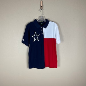 May include: A blue, white, and red short-sleeved polo shirt with a white star on the left chest. The shirt is designed to look like the Texas state flag.