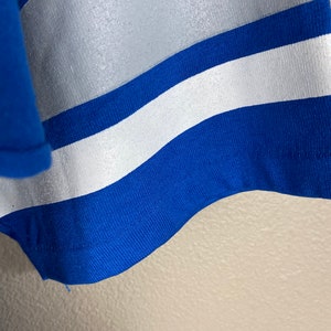 Puede incluir: Primer plano de una tela a rayas azul y blanca. La tela tiene una textura lisa y brillante.