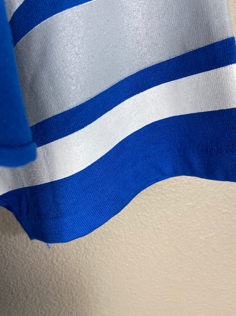 Puede incluir: Primer plano de una tela a rayas azul y blanca. La tela tiene una textura lisa y brillante.