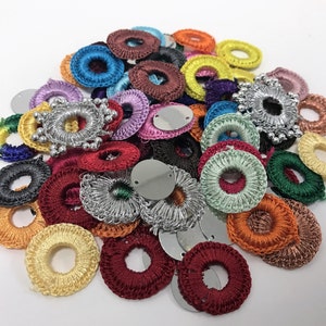 Peut inclure: Une collection de cercles en crochet de différentes couleurs avec divers embellissements, notamment des paillettes et des perles. Les cercles sont disposés de manière aléatoire et sont parfaits pour les projets d'artisanat.