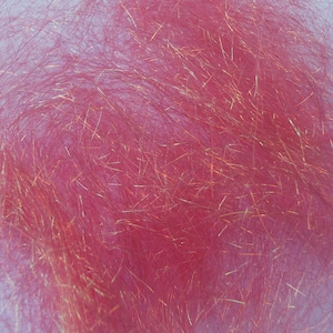 May include: Close-up of pink synthetic craft material with gold metallic strands. The material has a fluffy, textured appearance, with the gold strands interspersed throughout the pink fibers. The fibers are densely packed, creating a soft, shimmering effect.