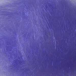 May include: Close-up of a pile of lavender-colored craft material. The material has a fluffy, fibrous texture with many thin, shiny strands. The strands catch the light, creating a shimmering effect. This material is likely used for crafting or decorative purposes.