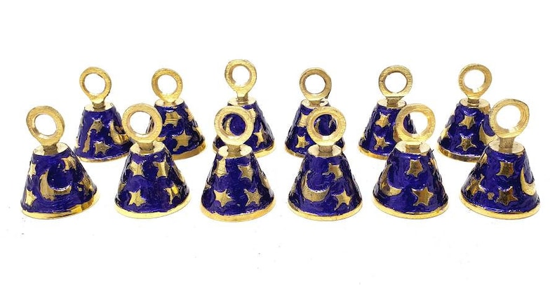 May include: Twelve small gold bells with blue enamel and gold stars and crescent moons. The bells have a loop at the top for hanging.