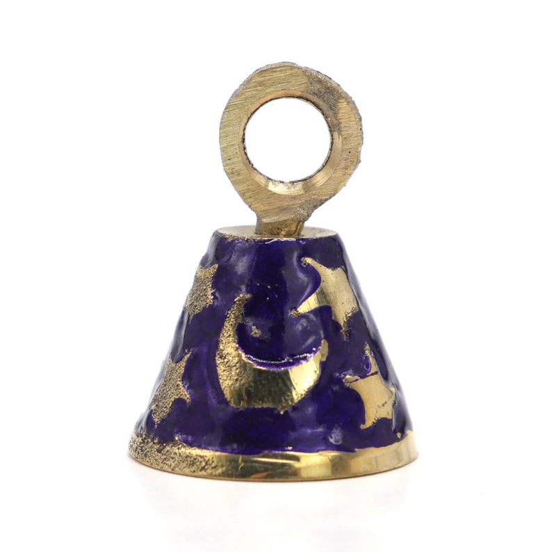 May include: A small brass bell with a blue enamel finish and a gold crescent moon and star design. The bell has a loop at the top for hanging.