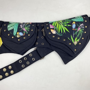May include: Black fanny pack with two zippered pockets and a belt. The pockets are decorated with a tropical print of parrots and foliage. Gold-colored rivets and rings accent the pack. The tag reads "crous barcelona".
