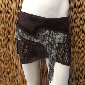 Puede incluir: Una falda de capas marrón y gris con una superposición de malla. La falda tiene un estampado floral y está hecha de una tela suave y fluida.