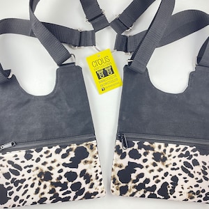 May include: Two black canvas crossbody bags with leopard print fabric lining the bottom. The bags have adjustable straps and a zipper closure. The bags are labeled with the text "CIOUS FASHION CREATIONS" and a website address.