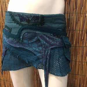 Può includere: Una gonna blu turchese con un design a strati. La gonna è realizzata con diversi tessuti, tra cui pizzo, rete e cotone. La gonna ha uno stile unico e bohémien.