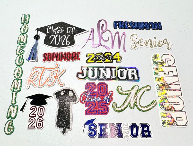 May include: A collection of colorful graduation themed iron-on patches. The patches feature various graduation year numbers, class of, senior, freshman, junior, sophomore, and homecoming.