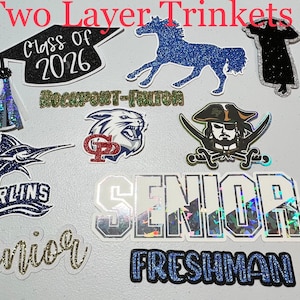 May include: A collection of 10 glitter and holographic iron-on patches featuring school mascots, graduation caps, and the words "Class of 2026", "Senior", and "Freshman".
