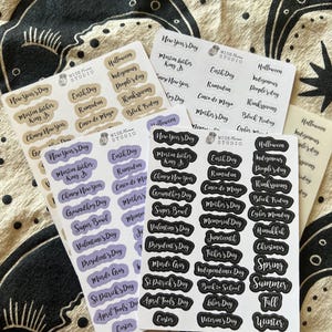 May include: Several sheets of stickers with various holiday and event names, including "New Year's Day," "Halloween," and "Thanksgiving." The stickers are in different colors, with text in a handwritten style. The brand name "WISE STUDIO" is printed on the stickers.