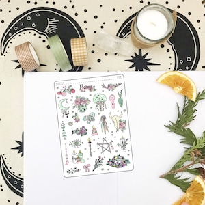May include: A sheet of stickers with a variety of illustrations related to the pagan holiday of Beltane. The stickers feature images of flowers, candles, a crescent moon, a pentagram, a skull, a tree, and a woman in a flowing dress. The text "Beltane" is printed at the top of the sheet.