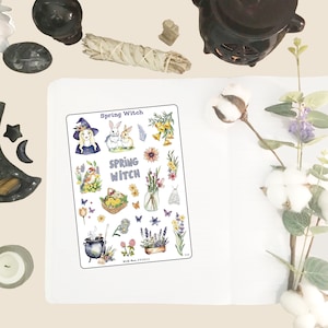 May include: A sheet of stickers featuring a witch with a purple hat and a white dress, two bunnies, a bird, flowers, a cauldron, and the text "Spring Witch".