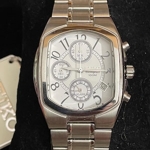 May include: A silver Seiko chronograph watch with a white face. The watch has multiple sub-dials, a date window, and a stainless steel strap. The watch face displays the numbers 1 to 12, with the Seiko logo at the top.