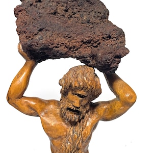 May include: A wooden sculpture of a man holding a large, dark brown rock above his head. The rock is labeled "Etna's lava, a unique rock".