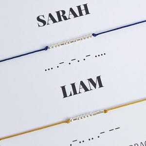 May include: A white card with the words "SARAH" and "LIAM" printed in black. Two bracelets with silver beads are shown on the card. The bracelets are made of blue and yellow string. The card also includes the text "925 SILVER MORSE CODE BRACELETS" and the social media handle "@florinejewelry".