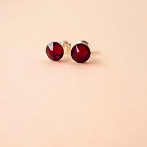 May include: A pair of silver stud earrings with red crystal stones.