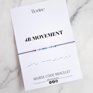 May include: A white card with the text "Florine" and "4B Movement" in black. The card also features a blue string bracelet with blue and gold beads. The bracelet is a Morse code bracelet with the code for "4B" written below it. The card also includes the text "Morse Code Bracelet" and the social media handle "@florinejewelry".