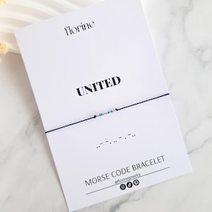 Può includere: Un braccialetto di corda blu con perline bianche che compongono la parola "UNITED" in codice Morse. Il braccialetto è su una carta bianca con le parole "UNITED" e "BRACCIALE CODICE MORSE" stampate su di essa.