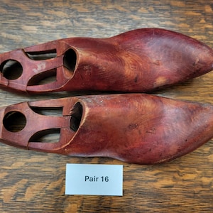 Puede incluir: Un par de hormas de zapatos de madera, o formas de zapatos, de color marrón rojizo. Las hormas están marcadas con "Pair 16".